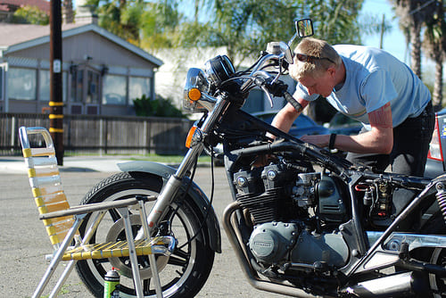 バイクの整備に夢中になる男性の画像